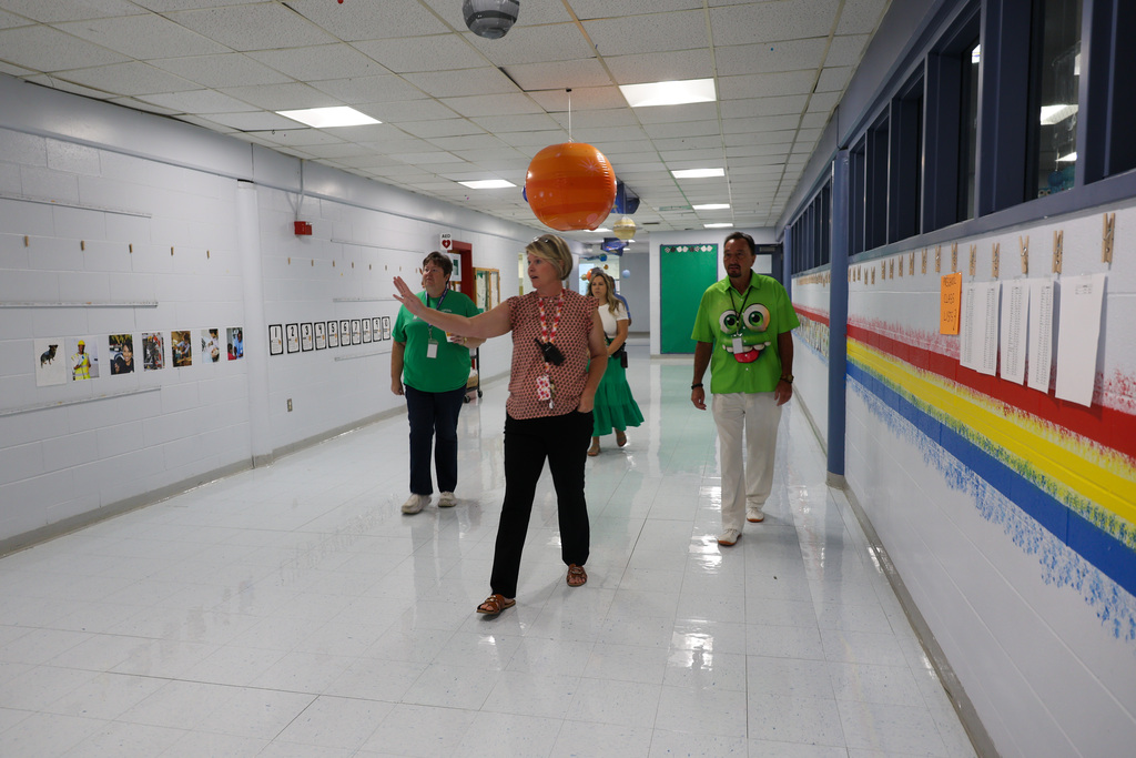 Principal Lynette McKinney leads board members and staff through the school hallway for a tour.