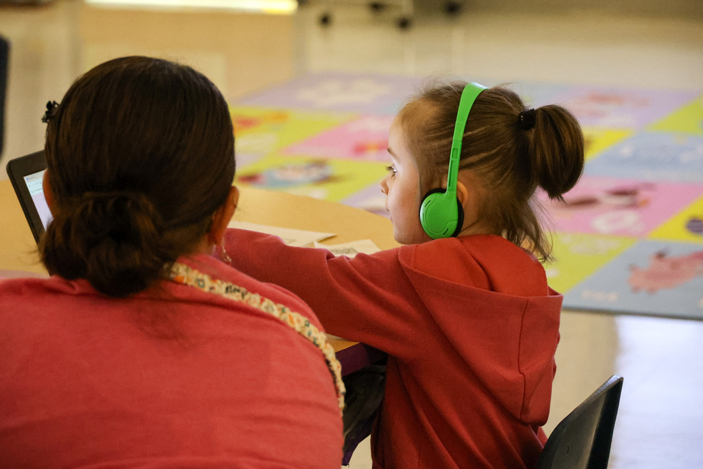 ELV teacher assists student sitting at a desk.