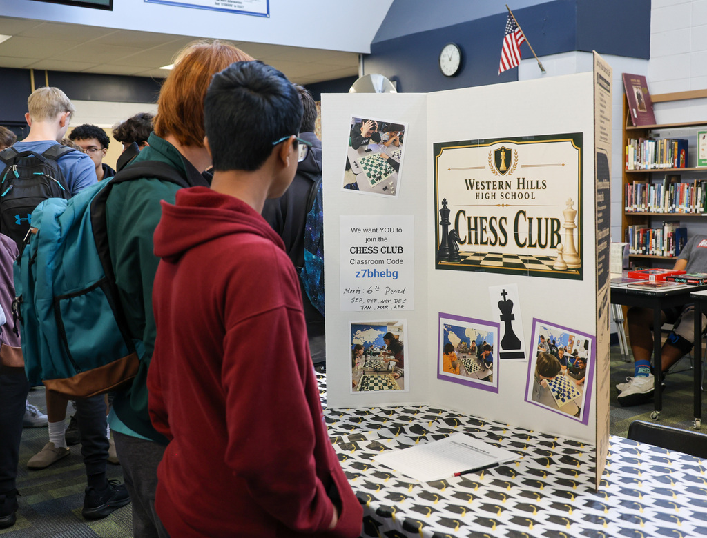 Two students look at the posterboard for the chess club.