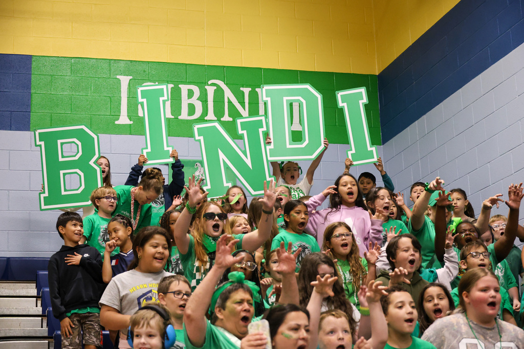 Isibindi section in all green cheering. Students are standing in the back holding big letters that spell out "BINDI"