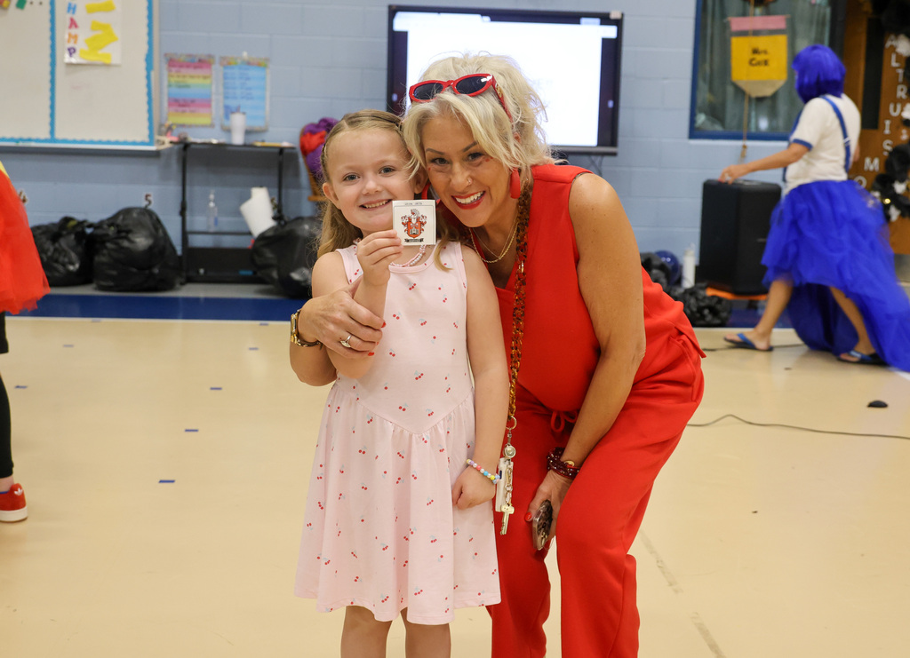 Student smiles with staff member holding up the sticker for her new nest.