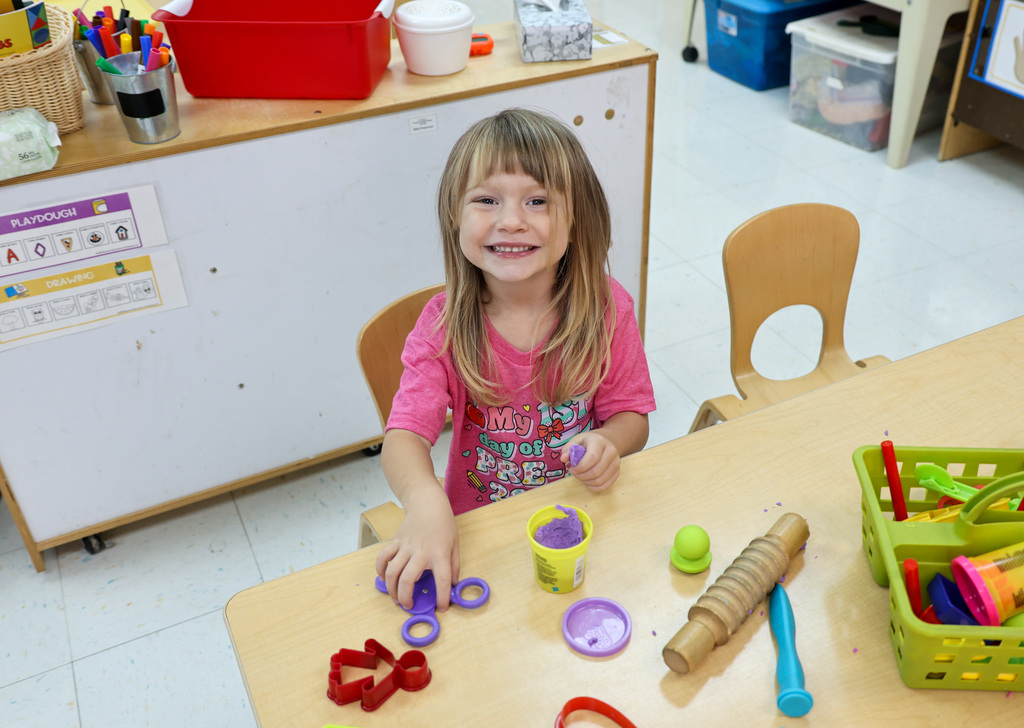 preschool student smiles while playing with play-doh