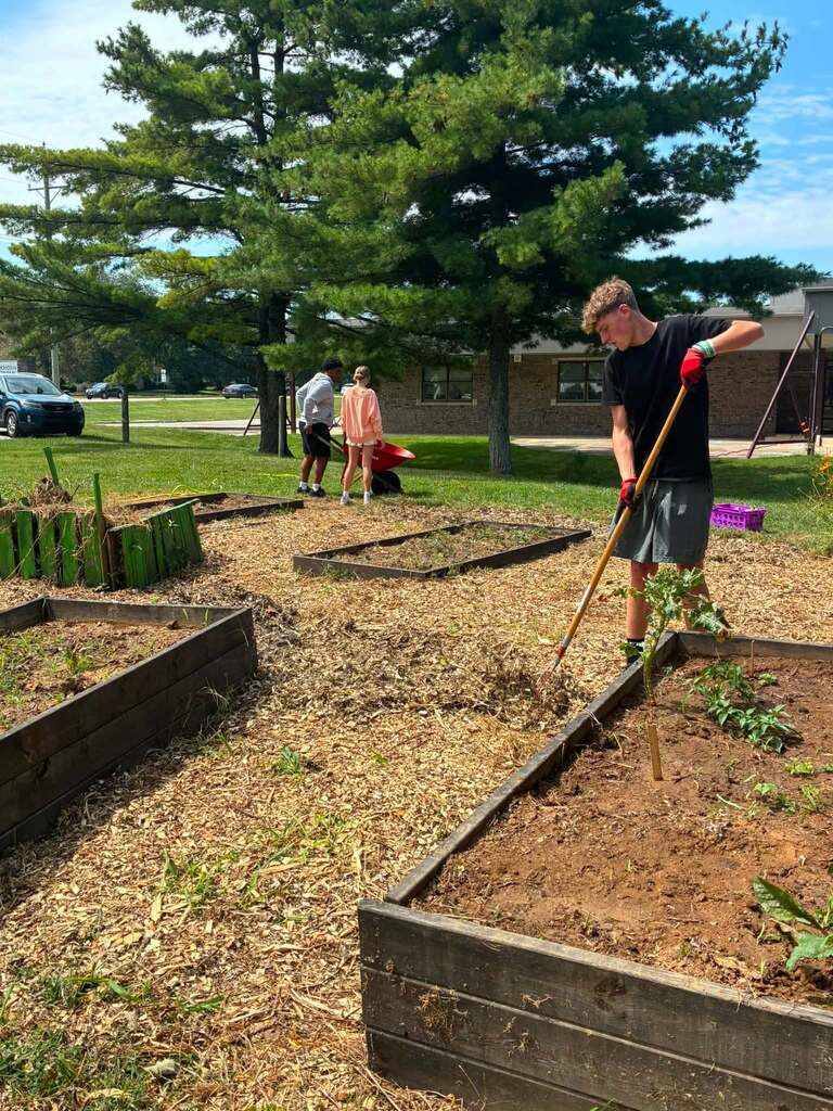 EMS student uses rake to work in on the school's garden.