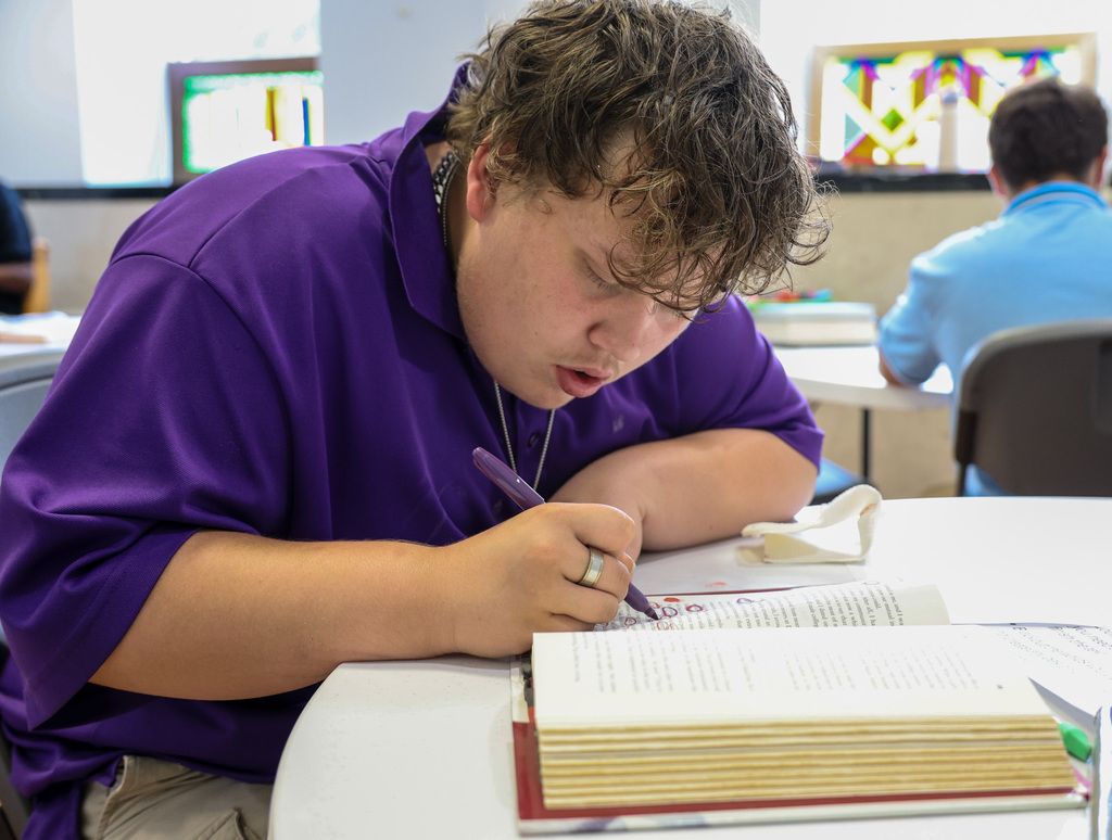 Academy student circles words in his book.