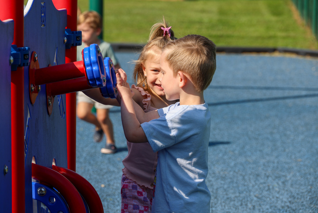 Two preschool students play on the playground.