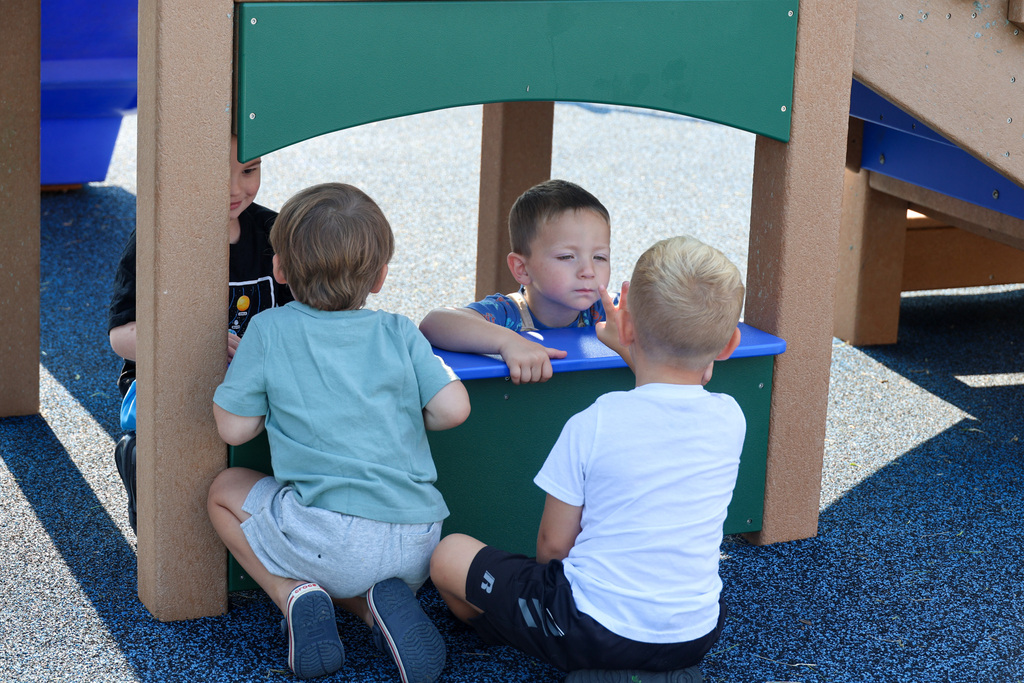 Four preschool students play on the playground together.