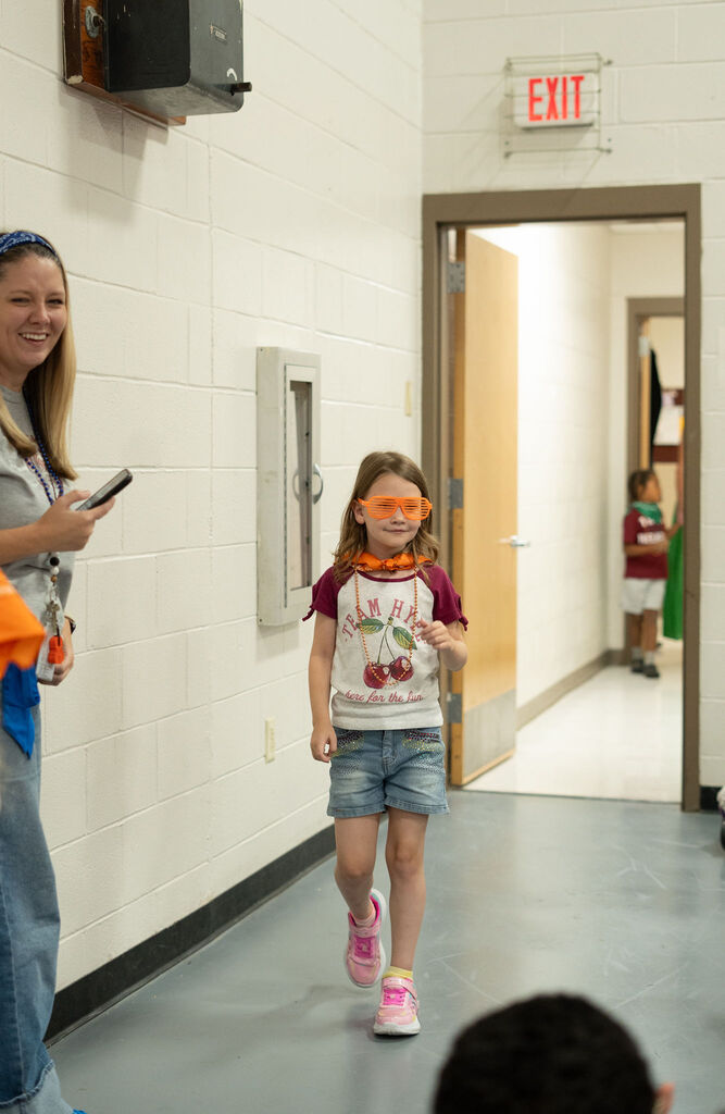 A student dressed in orange walks into the gym.