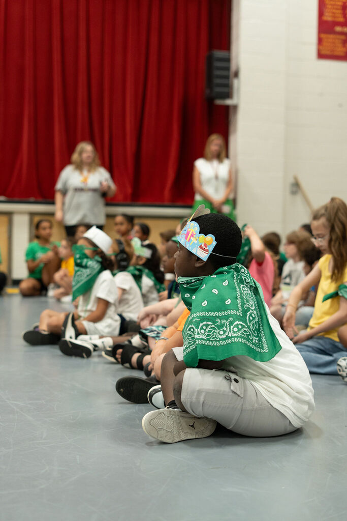 Student dressed in green (for the green herd) sits in the gym and listens.