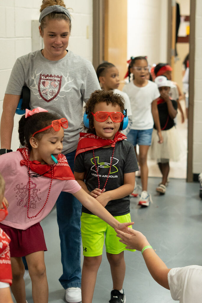 Students in red (for the red Herd) walk in the gym and give high five to students.
