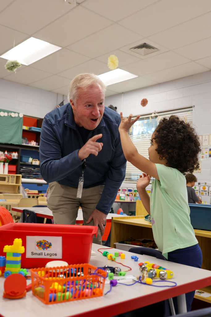 Superintendent Kopp interacts with student showing him the colors of the Legos.