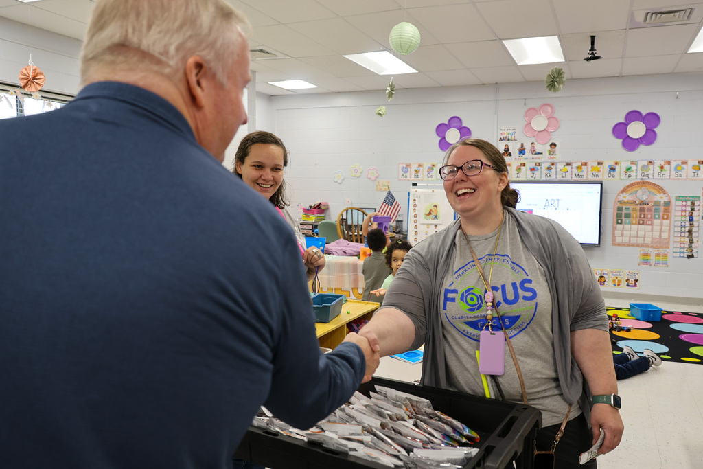 Superintendent Kopp shakes hands with a preschool teacher.