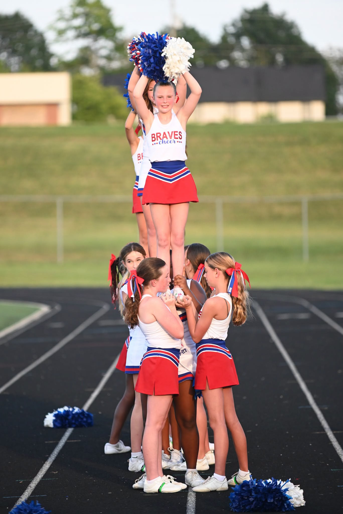 BMS cheerleaders lift a girl and she cheers on the track.