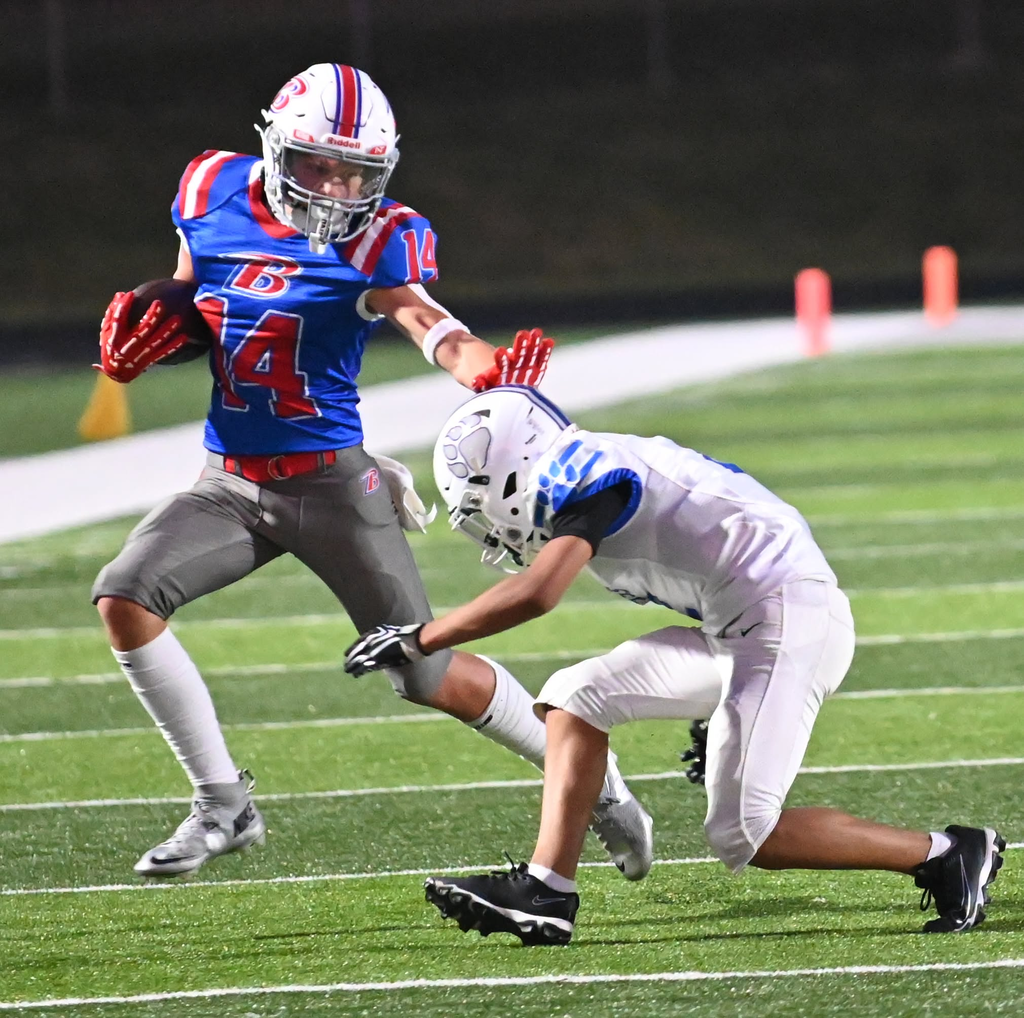 BMS football player extends arm to stop a player from tackling him.