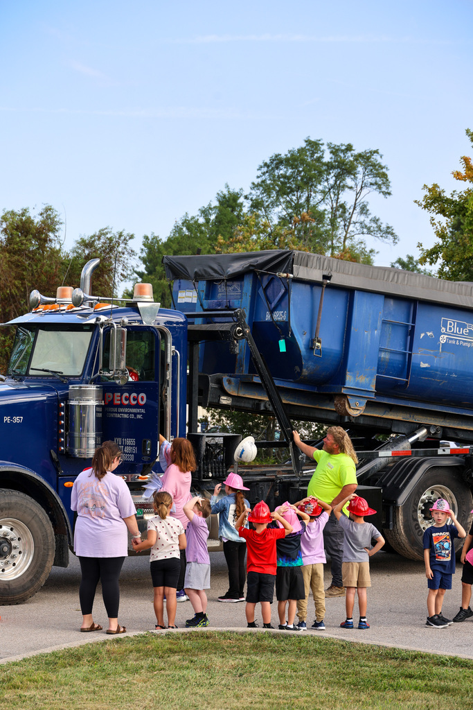 Students look at a large blue dump truck.