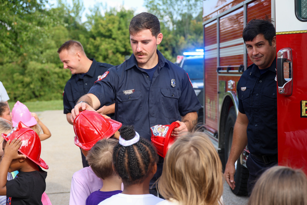 Firefighter gives student a firefighter hat.