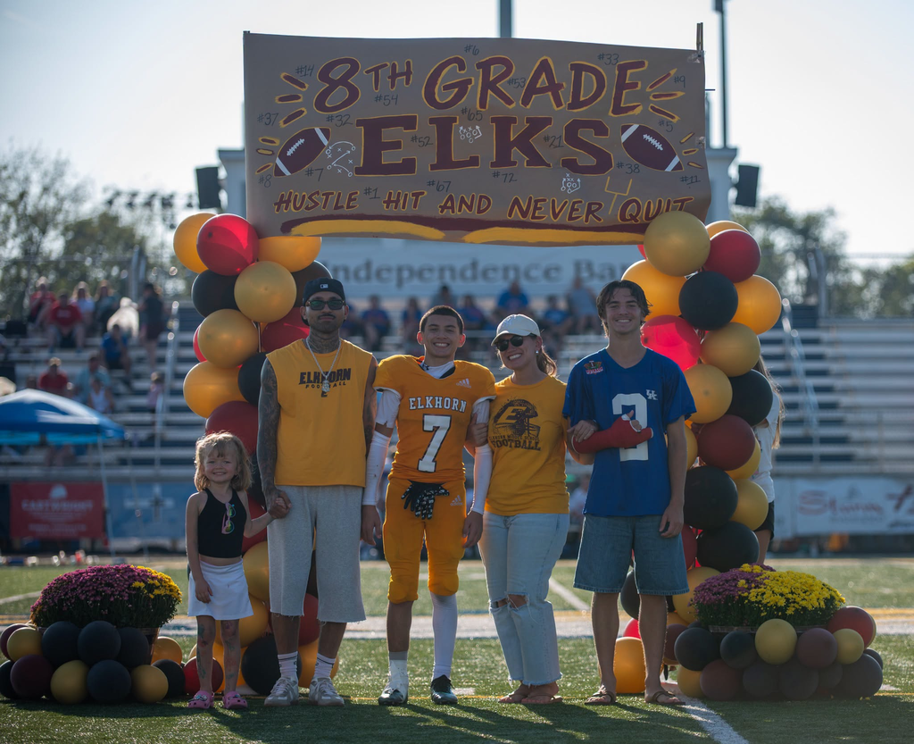 8th grade night. Football player stands with family to be recognized.