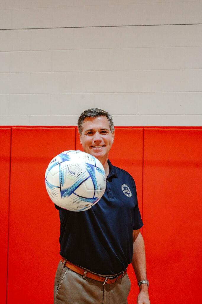 FIFA representative holds soccer ball with one hand.