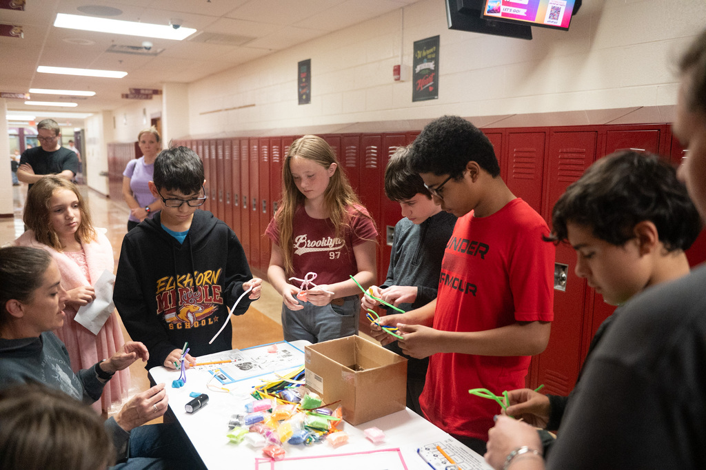 Students gather around one table to work on a project.