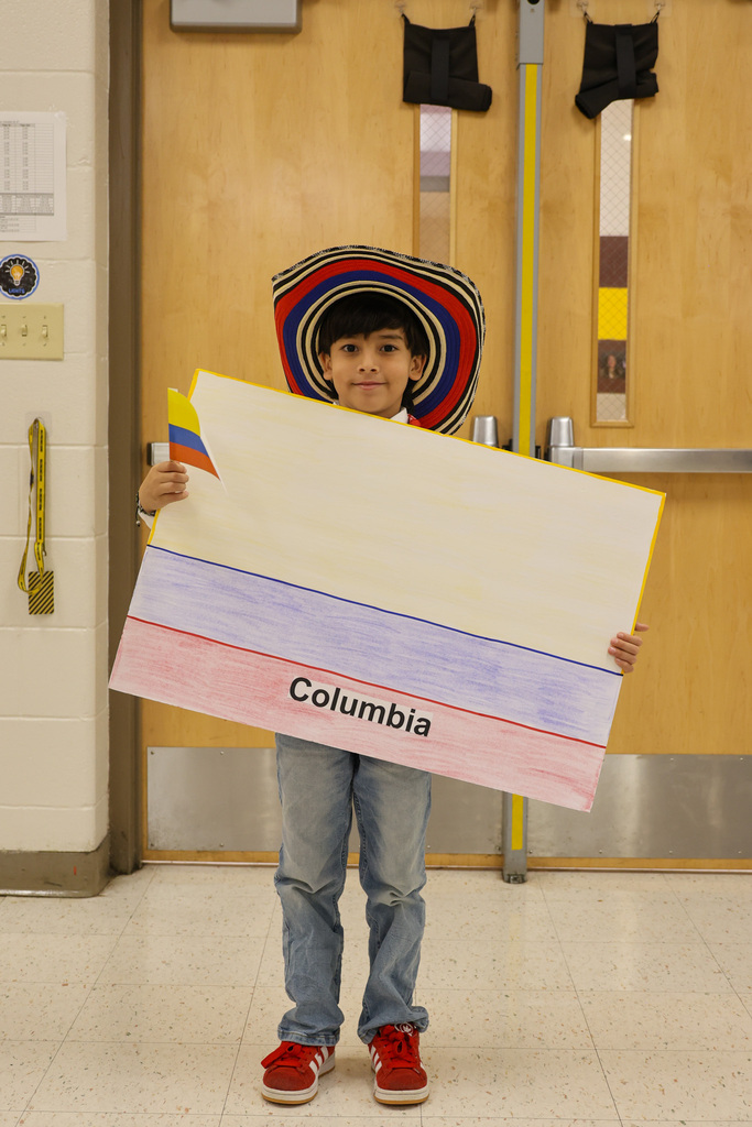 A student holds a sign with the Columbia flag and is wearing a colored hat with the flag colors and is holding a flag.