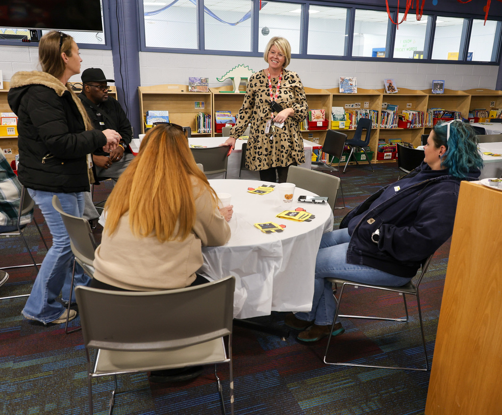 Principal Lynette McKinney speaks to transportation team members in the ELV library. The principal is standing and the team members are sitting at a table looking at her.