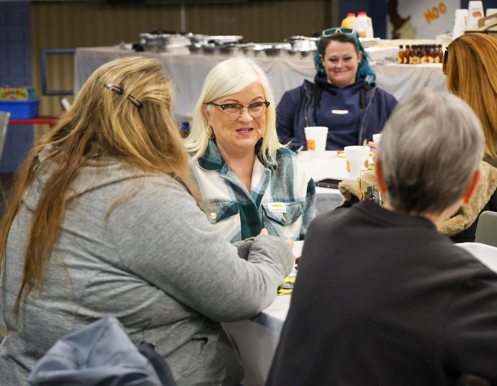 Transportation team member smiling and talking at the table with other team members.