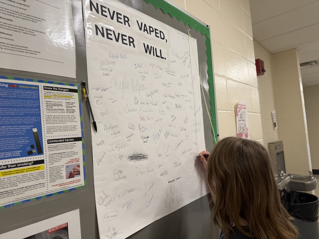 Student signs the bulletin board that says "Never Vaped, Never Will"