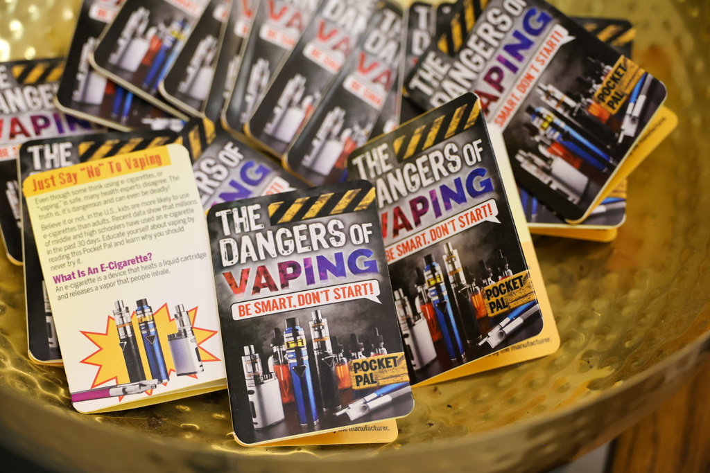 A basket of mini trifolds that say "The Dangers of Vaping."