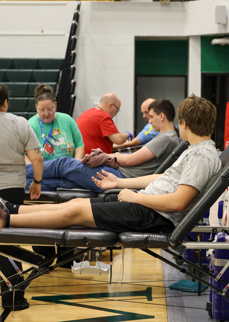 Three men sit in their chairs to give blood.
