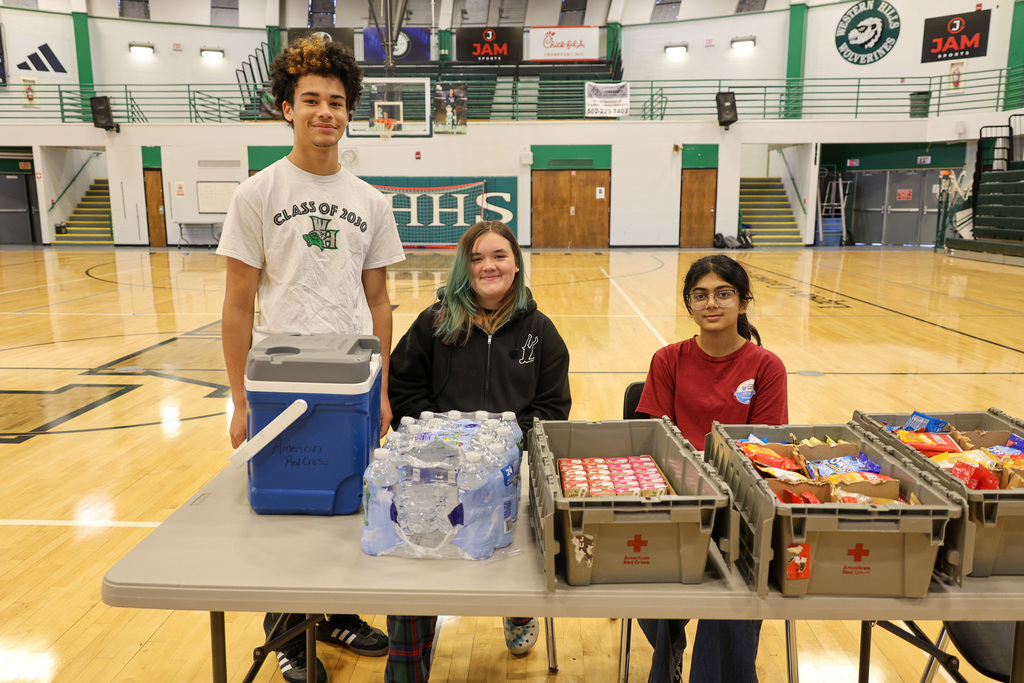 Three student HOSA club members smile at the refreshments table.