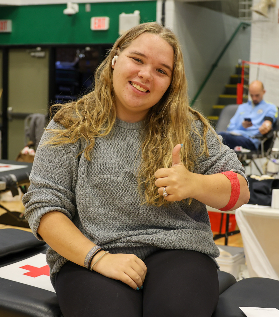 A woman gives a thumbs up after donating blood.
