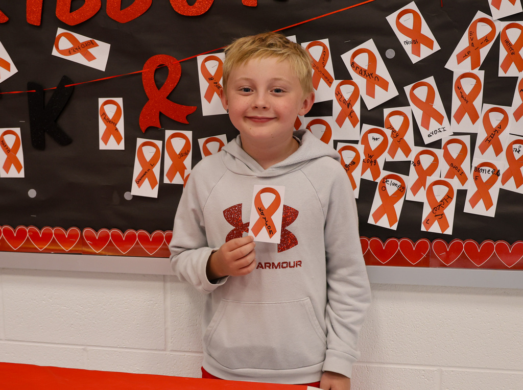 Student smiles with his red ribbon.
