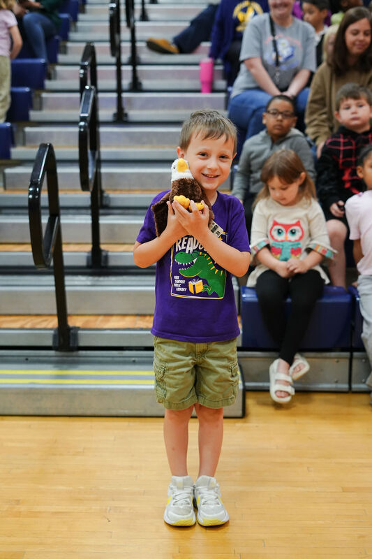 ELV students smiles with his stuffed animal eagle holding it close to his face.