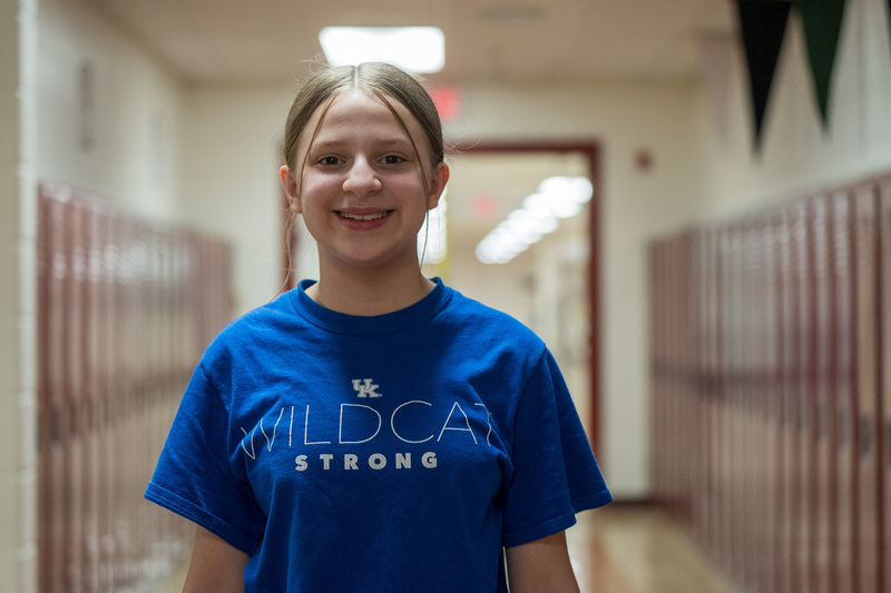 student in hallway - blueshirt red lockers