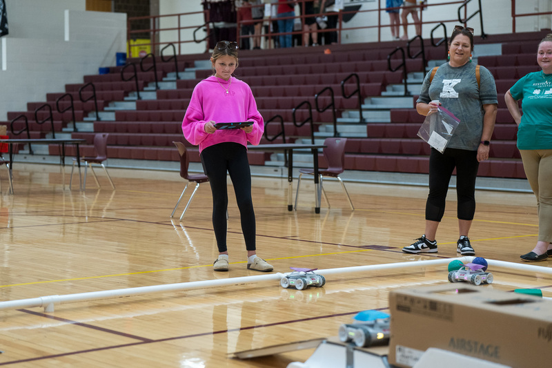 girl playing with sphero robots. She has a pink shirt on and black pants. She is in EMS' gym.