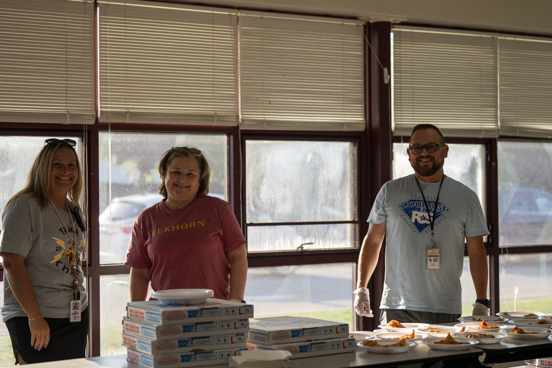 three people serving pizza