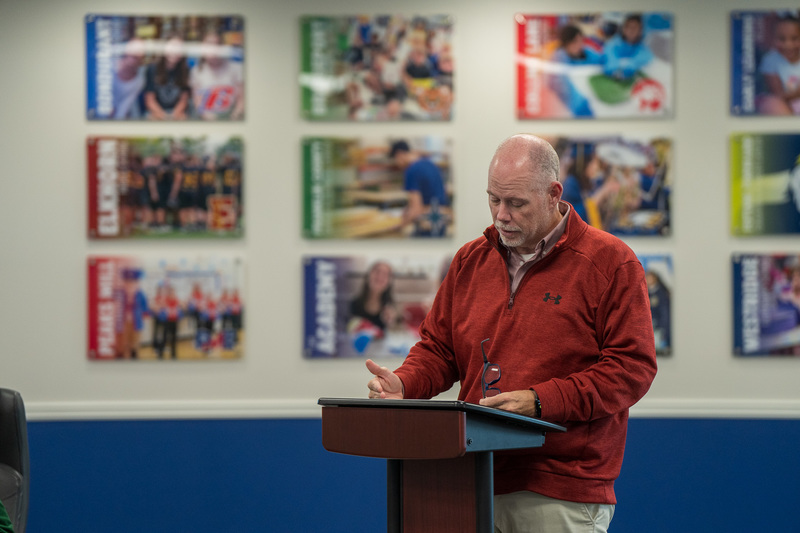 Chris Tracy stands at a podium in the board room.