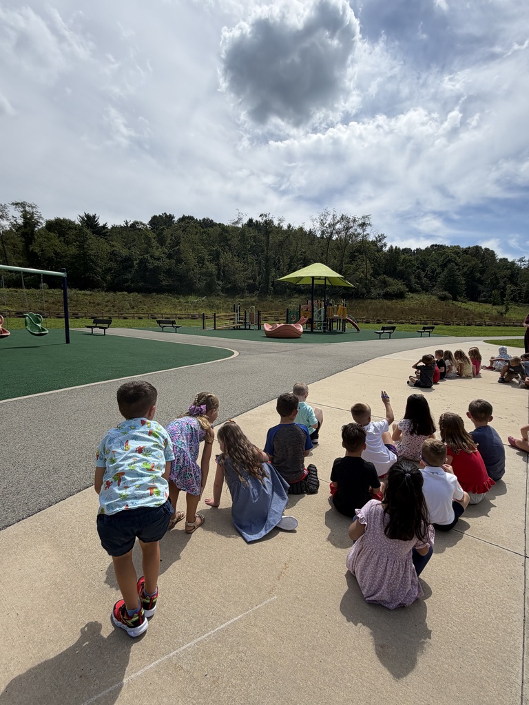 Several students sit on a playground outside.