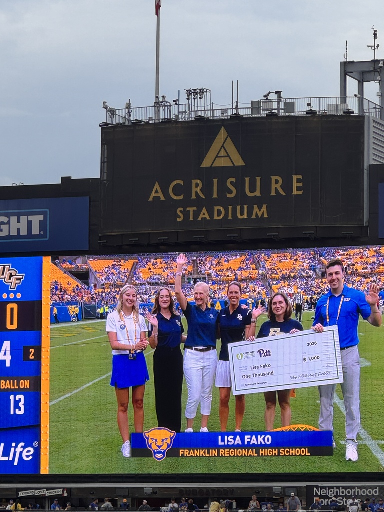 A large screen showing a scoreboard with the score 0 to 13. Five individuals stand in front of it, holding a large check.