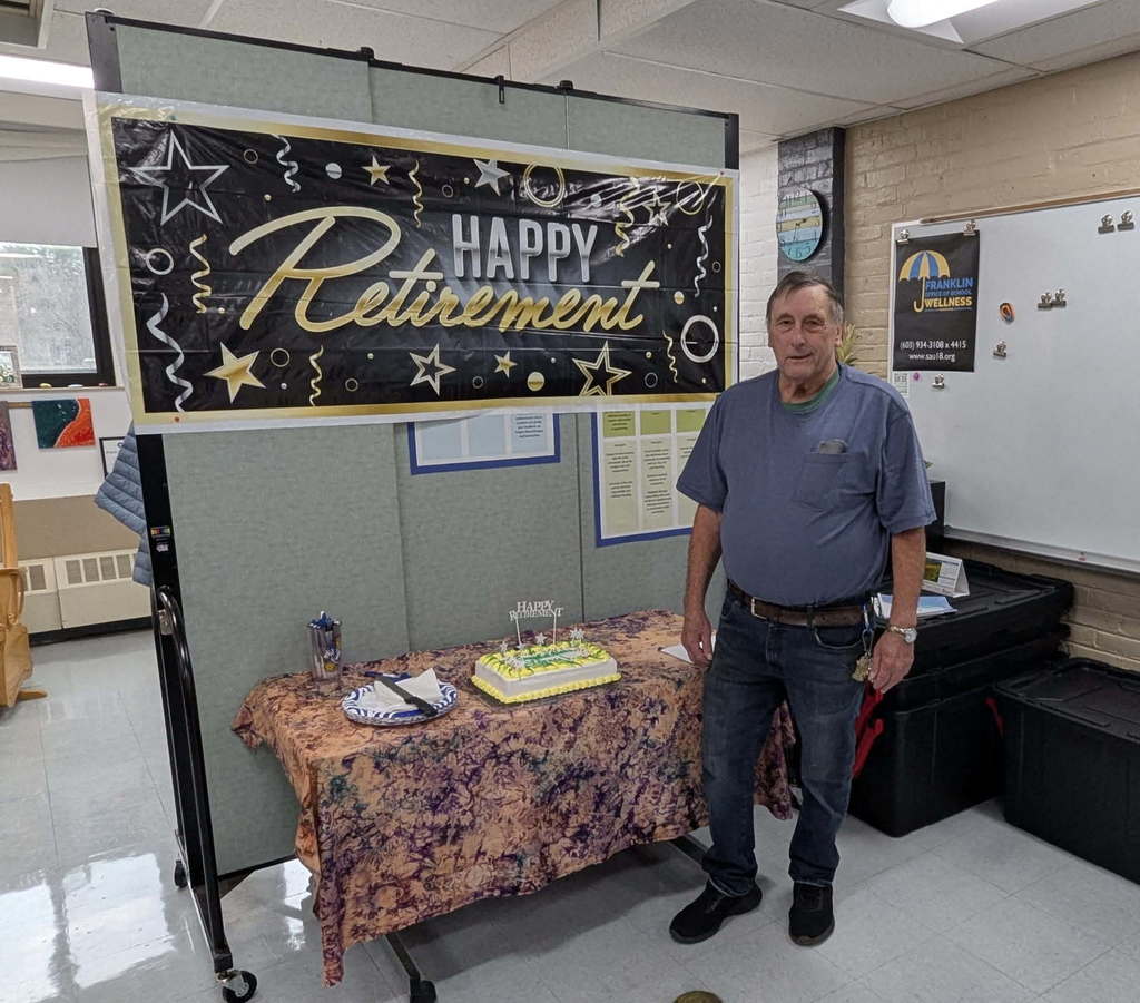 man in blue shirt in front of a Happy Retirement banner and cake