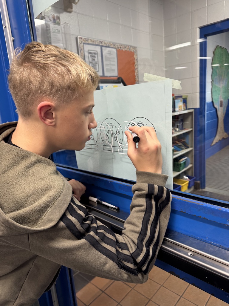 Middle School boy drawing Christmas decorations on entrance door
