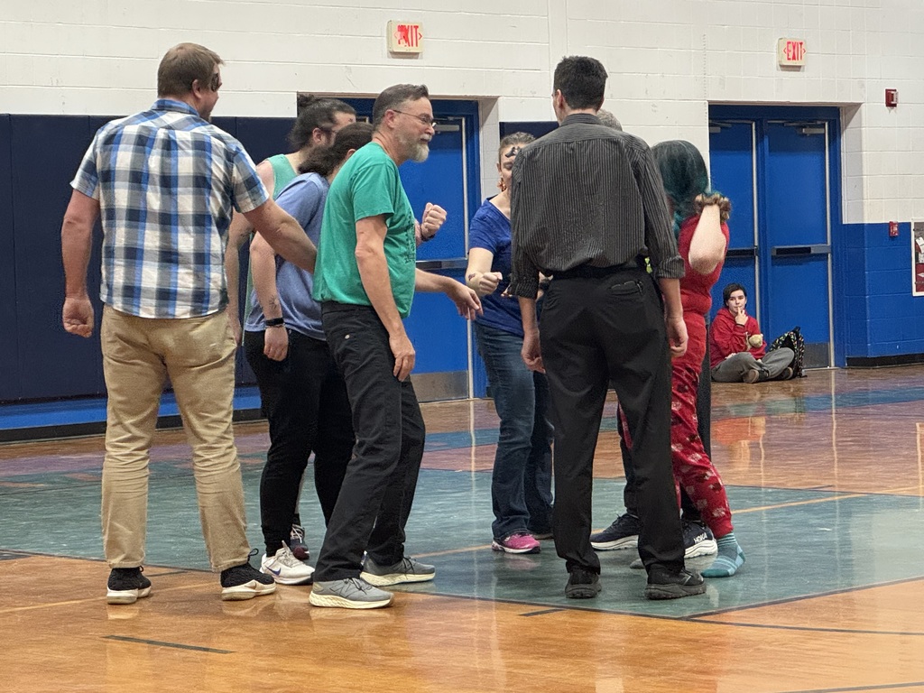 Teachers gathered in a circled on the basketball court 