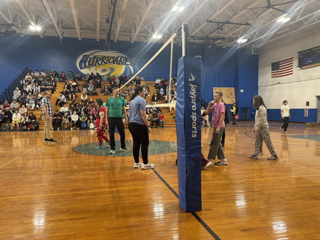 Volley ball game with bleachers full of fans in distance