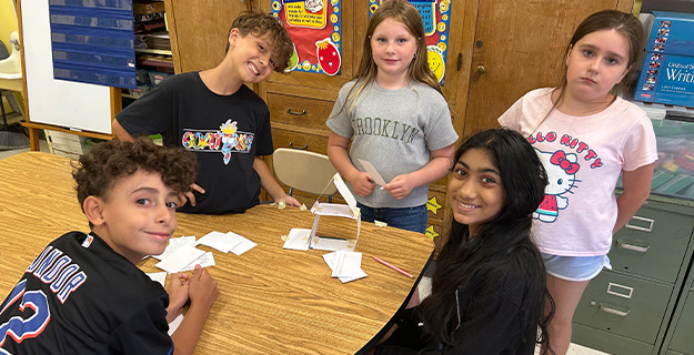 Students smiling at camera, sitting at table.