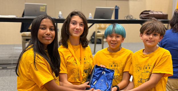Four students dressed in yellow holding their award.