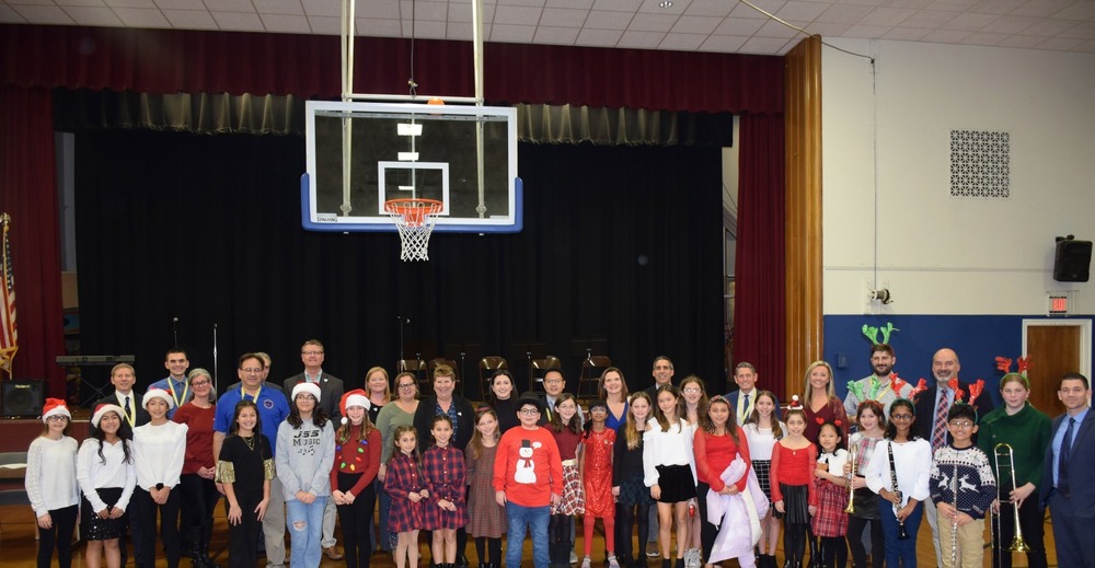 students in christmas attire in front of gymnasium stage