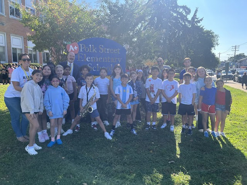 students outside in front of school sign