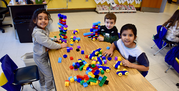 Students smiling while building with blocks.