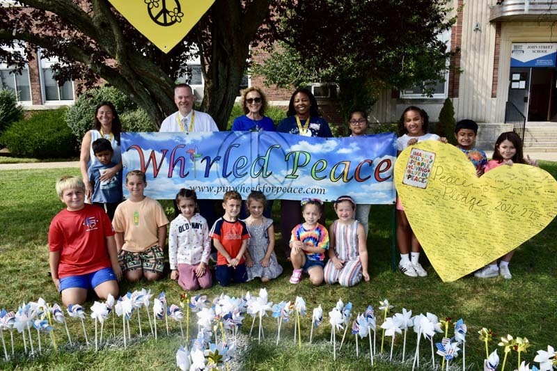 Students and teachers outside holding banner and art.
