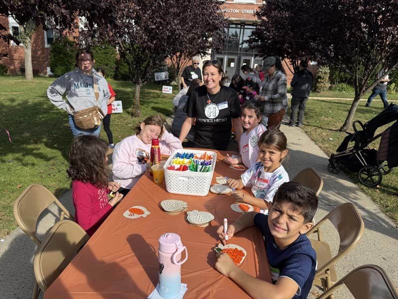 Students smiling otuside at table.