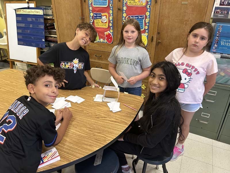 Students smiling at camera, sitting at table.